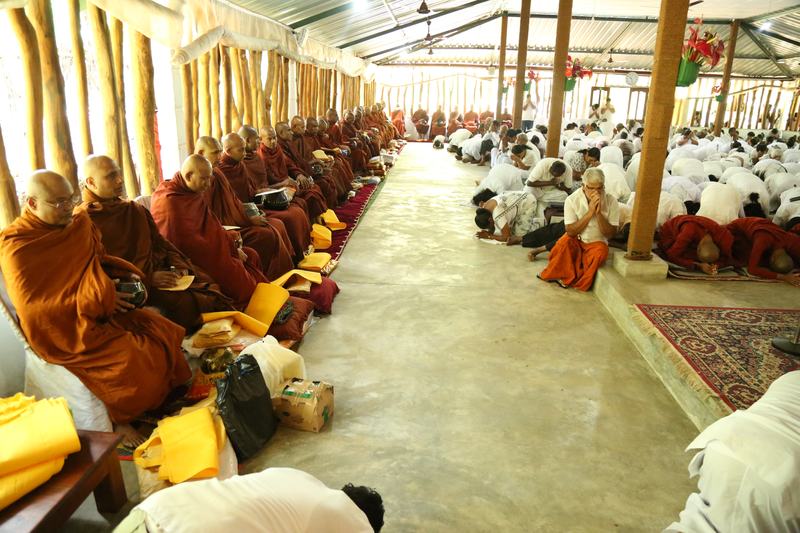 Monks seated for a Saṅghika dāna as devotees pay respects